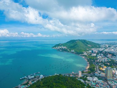 Vung Tau city aerial view with beautiful sunset and so many boats. Panoramic coastal Vung Tau view from above, with waves, coastline, streets, coconut trees and Tao Phung mountain in Vietnam.