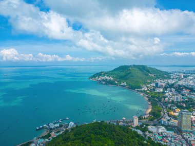 Vung Tau city aerial view with beautiful sunset and so many boats. Panoramic coastal Vung Tau view from above, with waves, coastline, streets, coconut trees and Tao Phung mountain in Vietnam.