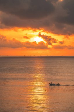 Beautiful cloudscape over the sea, sunrise shot. Lonely boats. Calm sea with sunset sky and sun through the clouds over. Calm sea with sunset sky or sunrise and sun through the clouds over.