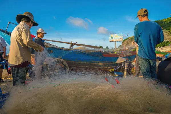 Vung Tau, VIETNAM - AUG 20 2022 : Fisherman casting his net at the sunrise or sunset. Traditional fishermen prepare the fishing net. Fishermen on beach at the Fishing.