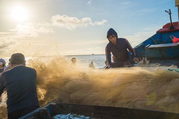 Vung Tau, VIETNAM - AUG 20 2022 : Fisherman casting his net at the sunrise or sunset. Traditional fishermen prepare the fishing net. Fishermen on beach at the Fishing.