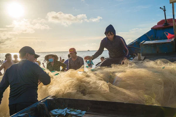 Vung Tau, VIETNAM - AUG 20 2022 : Fisherman casting his net at the sunrise or sunset. Traditional fishermen prepare the fishing net. Fishermen on beach at the Fishing.