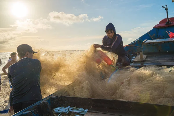 Vung Tau, VIETNAM - AUG 20 2022 : Fisherman casting his net at the sunrise or sunset. Traditional fishermen prepare the fishing net. Fishermen on beach at the Fishing.