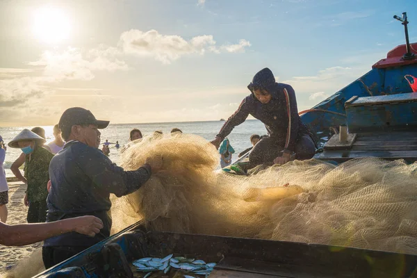Vung Tau, VIETNAM - AUG 20 2022 : Fisherman casting his net at the sunrise or sunset. Traditional fishermen prepare the fishing net. Fishermen on beach at the Fishing.