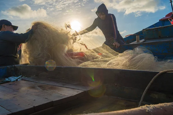 Vung Tau, VIETNAM - AUG 20 2022 : Fisherman casting his net at the sunrise or sunset. Traditional fishermen prepare the fishing net. Fishermen on beach at the Fishing.