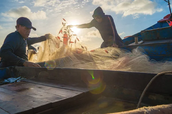 Vung Tau, VIETNAM - AUG 20 2022 : Fisherman casting his net at the sunrise or sunset. Traditional fishermen prepare the fishing net. Fishermen on beach at the Fishing.