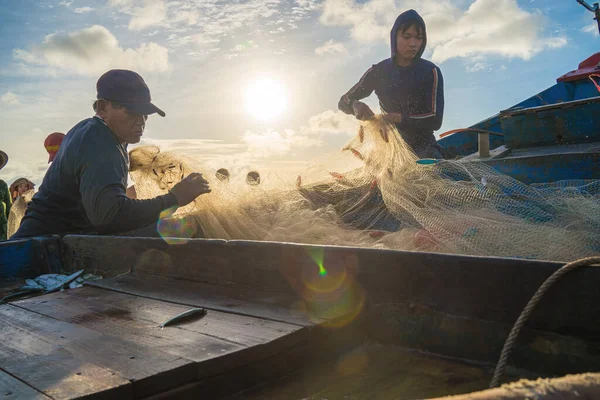 Vung Tau, VIETNAM - AUG 20 2022 : Fisherman casting his net at the sunrise or sunset. Traditional fishermen prepare the fishing net. Fishermen on beach at the Fishing.
