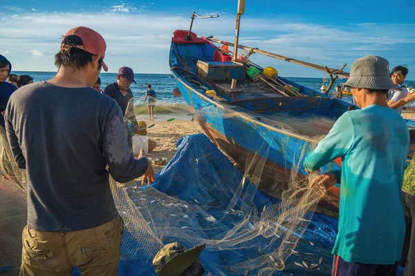 Vung Tau, VIETNAM - AUG 20 2022 : Fisherman casting his net at the sunrise or sunset. Traditional fishermen prepare the fishing net. Fishermen on beach at the Fishing.