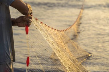 Fisherman casting his net at the sunrise or sunset. Traditional fishermen prepare the fishing net