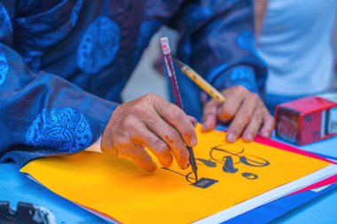 Vietnamese scholar writes calligraphy. Calligraphy festival is a popular tradition during Tet holiday. Writing couplets for Spring Festival, new year.