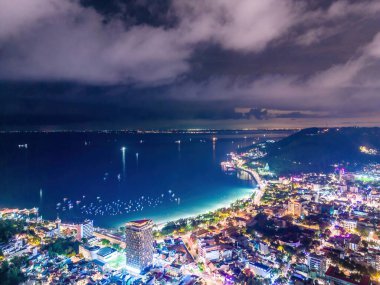 Vung Tau city aerial view with beautiful sunset and so many boats. Panoramic coastal Vung Tau view from above, with waves, coastline, streets, coconut trees and Tao Phung mountain in Vietnam.