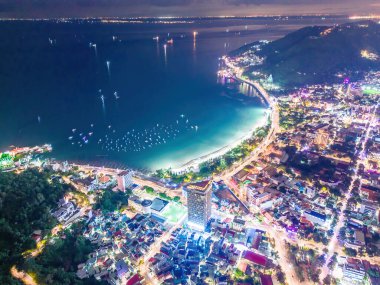 Vung Tau city aerial view with beautiful sunset and so many boats. Panoramic coastal Vung Tau view from above, with waves, coastline, streets, coconut trees and Tao Phung mountain in Vietnam.