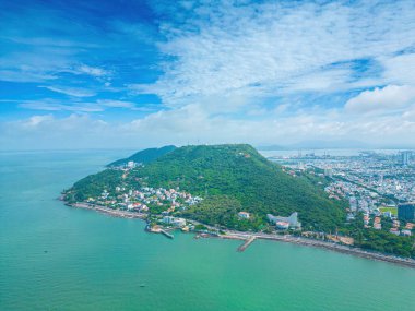 Vung Tau city aerial view with beautiful sunset and so many boats. Panoramic coastal Vung Tau view from above, with waves, coastline, streets, coconut trees and Tao Phung mountain in Vietnam.