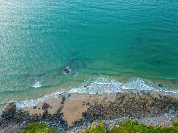 Aerial drone top view of ocean\'s beautiful waves crashing on the rocky island coast. Selective focus. Travel concept.