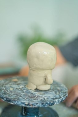 Woman potter working on potters wheel making ceramic pot from clay in pottery workshop. art concept. Focus hand young woman attaching clay product part to future ceramic product. Pottery workshop.