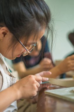 Woman potter working on potters wheel making ceramic pot from clay in pottery workshop. art concept. Focus hand young woman attaching clay product part to future ceramic product. Pottery workshop.