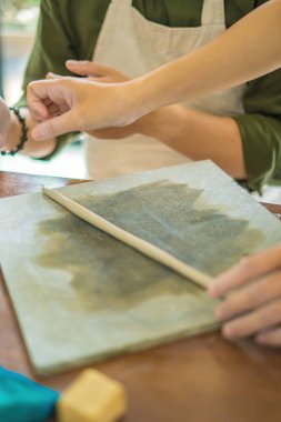 Woman potter working on potters wheel making ceramic pot from clay in pottery workshop. art concept. Focus hand young woman attaching clay product part to future ceramic product. Pottery workshop.