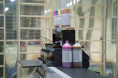 Close up CMYK ink bottles from a sublimation printer. Interior factory Large printing machine for paper business in printing room. Sublimation concept.