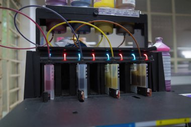 Close up CMYK ink bottles from a sublimation printer. Interior factory Large printing machine for paper business in printing room. Sublimation concept.