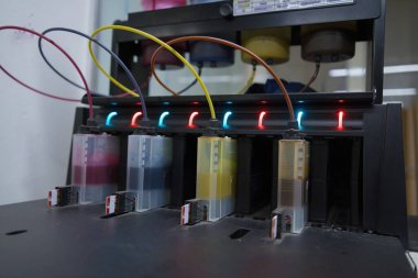 Close up CMYK ink bottles from a sublimation printer. Interior factory Large printing machine for paper business in printing room. Sublimation concept.