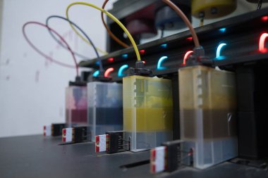 Close up CMYK ink bottles from a sublimation printer. Interior factory Large printing machine for paper business in printing room. Sublimation concept.