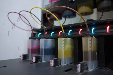 Close up CMYK ink bottles from a sublimation printer. Interior factory Large printing machine for paper business in printing room. Sublimation concept.