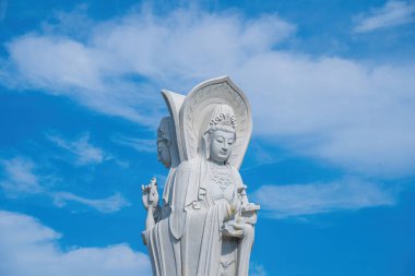 Majestic white Buddha statue on blue sky background. The Lady Buddha (the Bodhisattva of Mercy) at the Buu Lam Tu Pagoda which attracts tourists to visit spiritually on weekends in Vung Tau, Vietnam