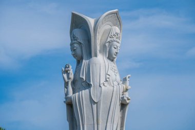 Majestic white Buddha statue on blue sky background. The Lady Buddha (the Bodhisattva of Mercy) at the Buu Lam Tu Pagoda which attracts tourists to visit spiritually on weekends in Vung Tau, Vietnam