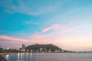 Vung Tau city aerial view with beautiful sunset and so many boats. Panoramic coastal Vung Tau view from above, with waves, coastline, streets, coconut trees and Tao Phung mountain in Vietnam.