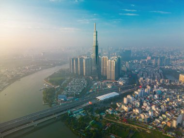 Aerial sunrise view at Landmark 81 - it is a super tall skyscraper and Saigon bridge with development buildings along Saigon river, cityscape in the beautiful morning with small fog around city
