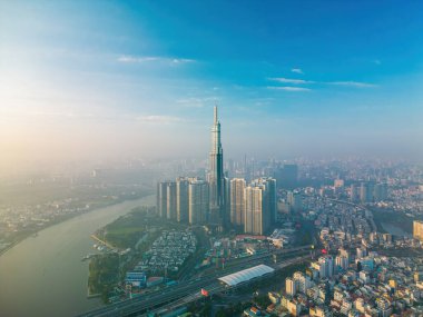 Aerial sunrise view at Landmark 81 - it is a super tall skyscraper and Saigon bridge with development buildings along Saigon river, cityscape in the beautiful morning with small fog around city