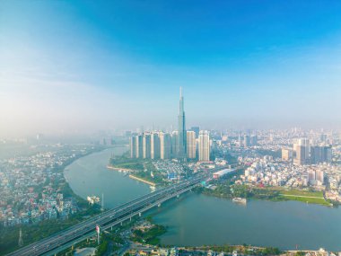 Aerial sunrise view at Landmark 81 - it is a super tall skyscraper and Saigon bridge with development buildings along Saigon river, cityscape in the beautiful morning with small fog around city