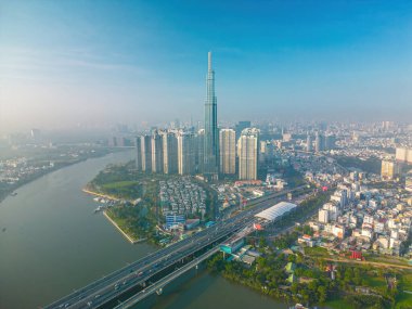 Aerial sunrise view at Landmark 81 - it is a super tall skyscraper and Saigon bridge with development buildings along Saigon river, cityscape in the beautiful morning with small fog around city