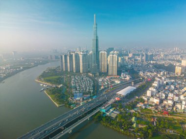 Aerial sunrise view at Landmark 81 - it is a super tall skyscraper and Saigon bridge with development buildings along Saigon river, cityscape in the beautiful morning with small fog around city