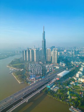 Aerial sunrise view at Landmark 81 - it is a super tall skyscraper and Saigon bridge with development buildings along Saigon river, cityscape in the beautiful morning with small fog around city