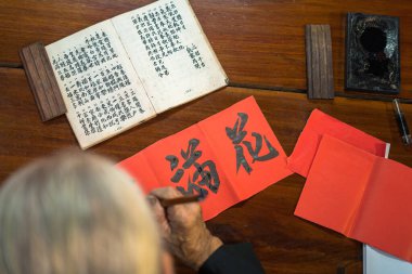 Vung Tau, Vietnam JAN 12 2023: Vietnamese scholar writes calligraphy at Long Son. Calligraphy festival is a popular tradition during Tet holiday. Writing couplets for Spring Festival, new year.