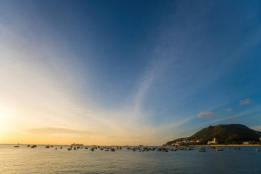 Vung Tau city aerial view with beautiful sunset and so many boats. Panoramic coastal Vung Tau view from above, with waves, coastline, streets, coconut trees and Tao Phung mountain in Vietnam.