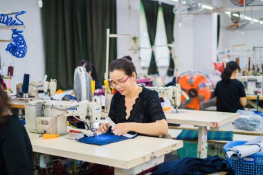 Ba Ria, VIETNAM - JAN 19 2023: Textile cloth factory working process tailoring workers equipment. This is a sewing machine factory production. portrait of professional Seamstress