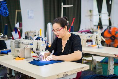 Ba Ria, VIETNAM - JAN 19 2023: Textile cloth factory working process tailoring workers equipment. This is a sewing machine factory production. portrait of professional Seamstress