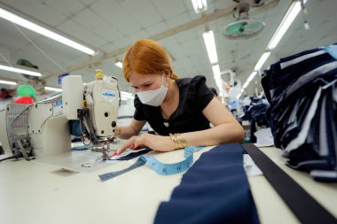 Ba Ria, VIETNAM - JAN 19 2023: Textile cloth factory working process tailoring workers equipment. This is a sewing machine factory production. portrait of professional Seamstress