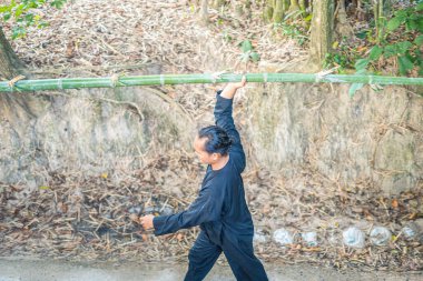 Vung Tau, Vietnam JAN 21 2023: Focus group old man with traditional Vietnamese cut bamboo tree to prepare Neu Tree, The bamboo pole placed in front of house on the last day of the lunar year