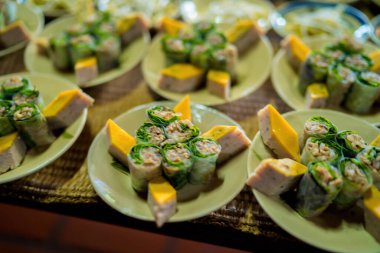 Top view of Vietnamese food for Tet holiday in spring, jam is traditional food and teapot set on lunar new year. Sticky rice ( banh tet) and srping roll on wooden table. Selective focus.