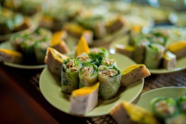 Top view of Vietnamese food for Tet holiday in spring, jam is traditional food and teapot set on lunar new year. Sticky rice ( banh tet) and srping roll on wooden table. Selective focus.