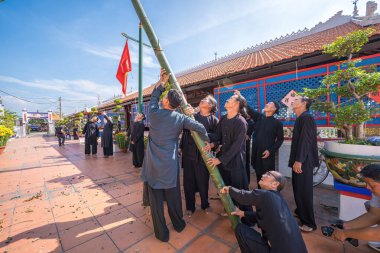 Vung Tau, Vietnam - JAN 21 2023: Raising Neu tree rituals in communal house at Long Son house. The bamboo pole placed in front of house on the last day of the lunar year to expel evils