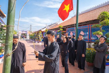 Vung Tau, Vietnam - JAN 21 2023: Raising Neu tree rituals in communal house at Long Son house. The bamboo pole placed in front of house on the last day of the lunar year to expel evils
