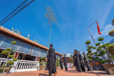 Vung Tau, Vietnam - JAN 21 2023: Raising Neu tree rituals in communal house at Long Son house. The bamboo pole placed in front of house on the last day of the lunar year to expel evils