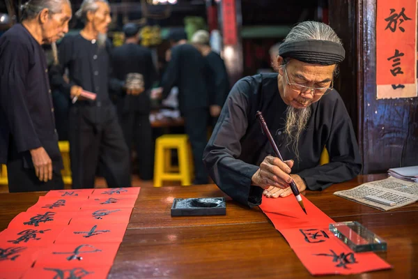 Vung Tau, Vietnam JAN 12 2023: Vietnamese scholar writes calligraphy at Long Son. Calligraphy festival is a popular tradition during Tet holiday. Writing couplets for Spring Festival, new year.