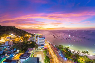 Vung Tau city aerial view with beautiful sunset and so many boats. Panoramic coastal Vung Tau view from above, with waves, coastline, streets, coconut trees and Tao Phung mountain in Vietnam.