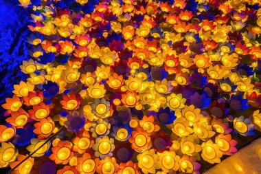 Floating colored lanterns and garlands on river at night on Vesak day day for celebrating Buddha's birthday at night, that made from paper and candle. Commemorating those who have passed away