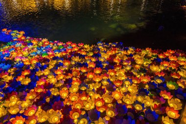 Floating colored lanterns and garlands on river at night on Vesak day day for celebrating Buddha's birthday at night, that made from paper and candle. Commemorating those who have passed away